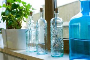 Decorative bottles from blue glass on a windowsill with flowers
